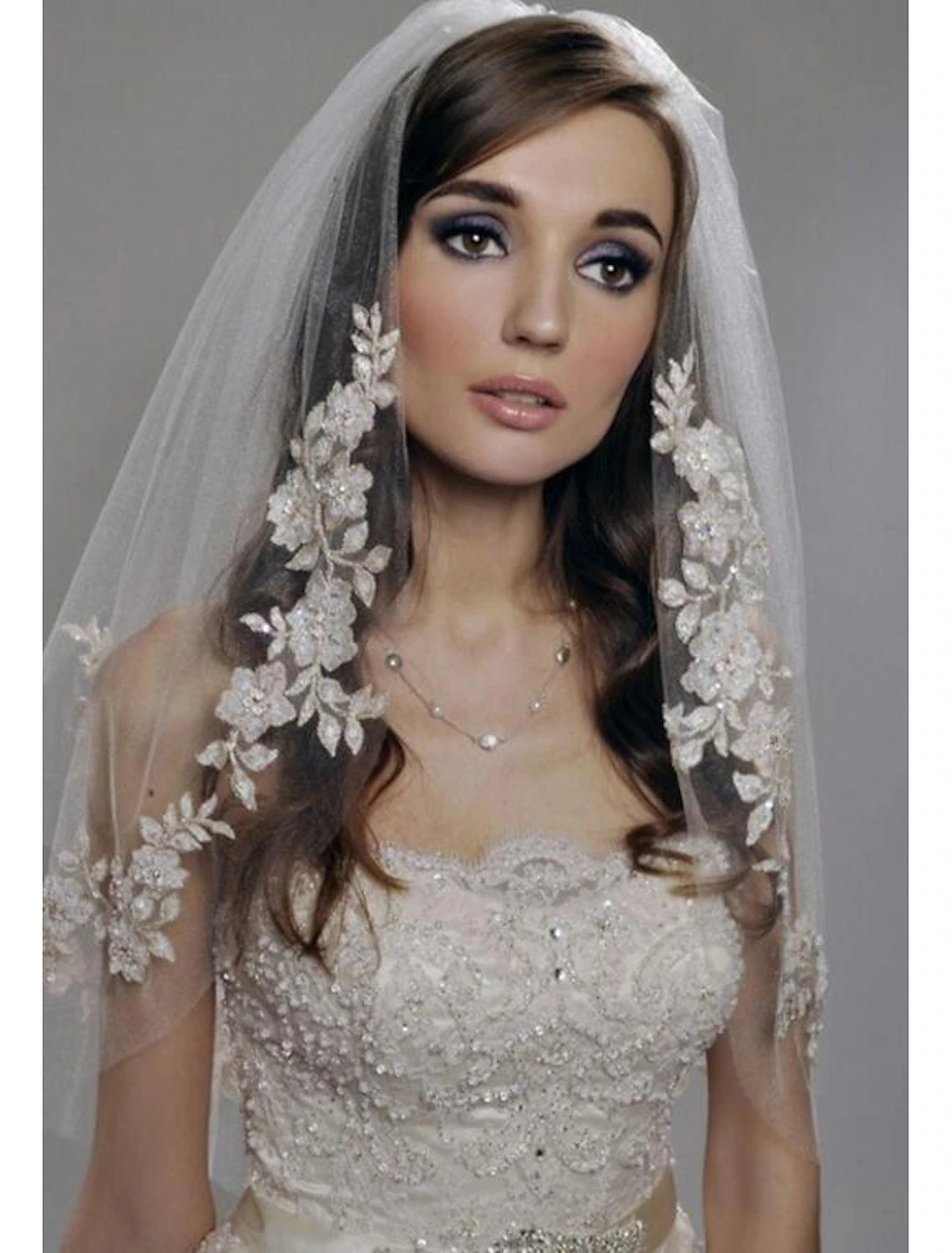 Bride wearing a stylish two-tier elbow wedding veil with faux pearls.