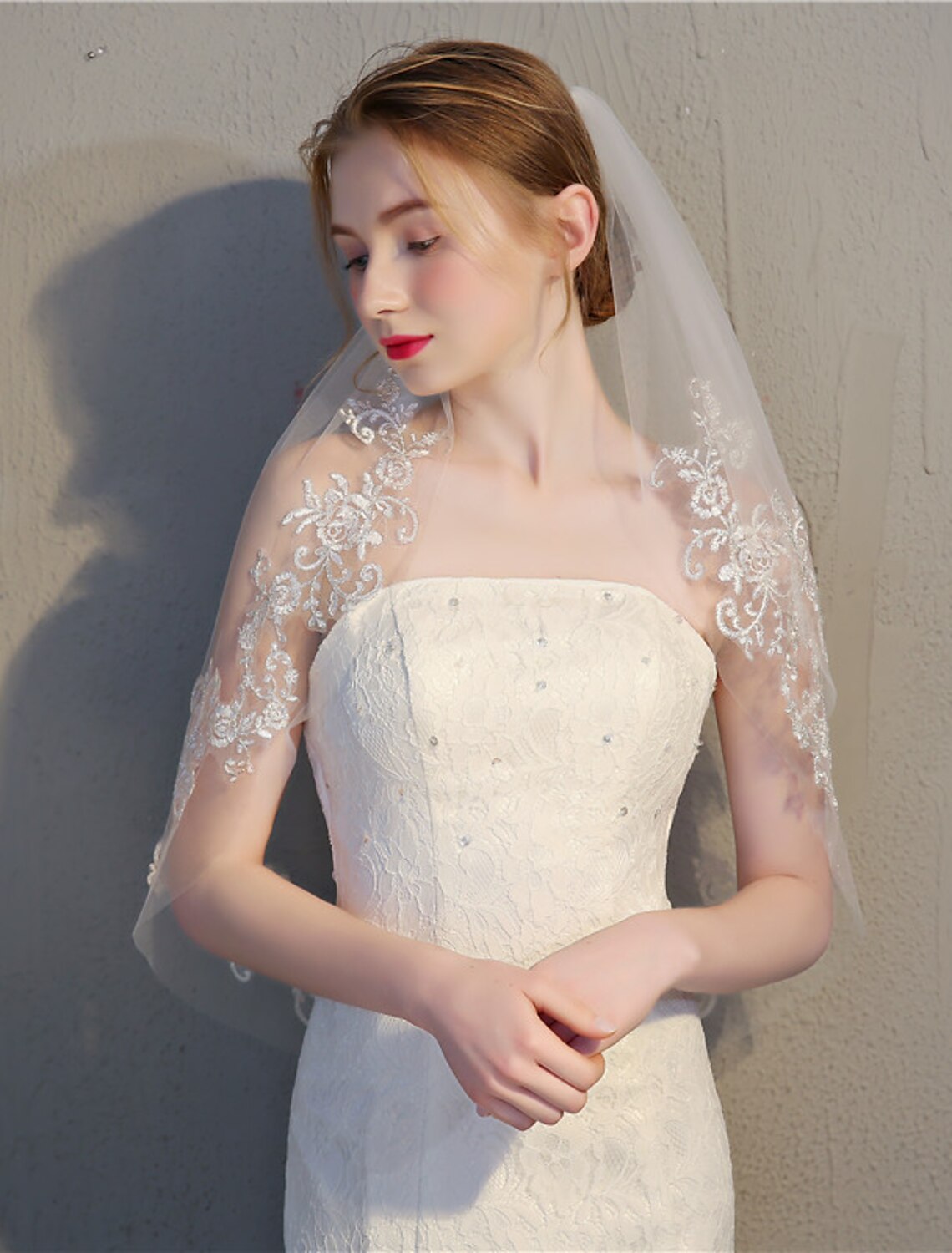 Model wearing a two-tier elbow wedding veil with delicate lace appliques.