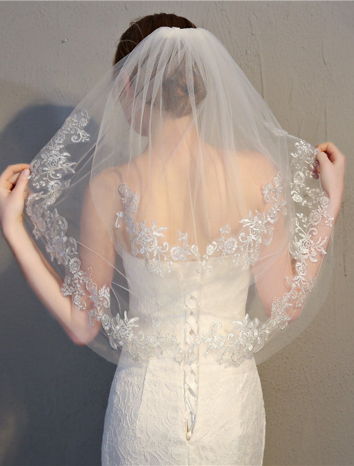 Close-up of the intricate lace appliques on the edge of the wedding veil.