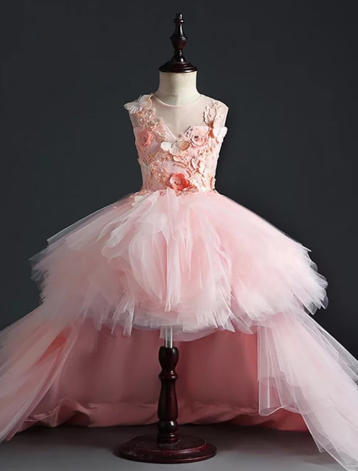 Little girl wearing a pink A-line ruched mesh dress with flower detail.