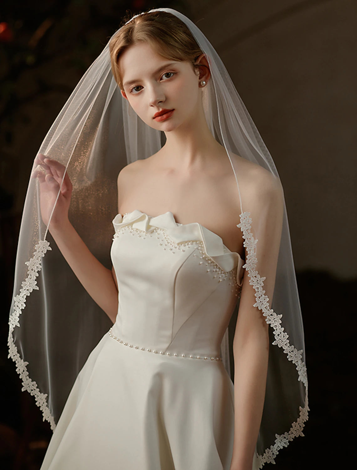 Bride wearing a sweet one-tier fingertip wedding veil made of pure tulle.