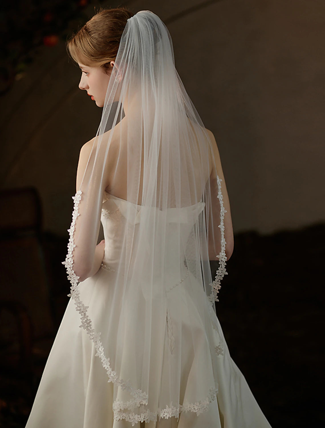 Close-up of a bride's back showing the elegant one-tier fingertip tulle veil.
