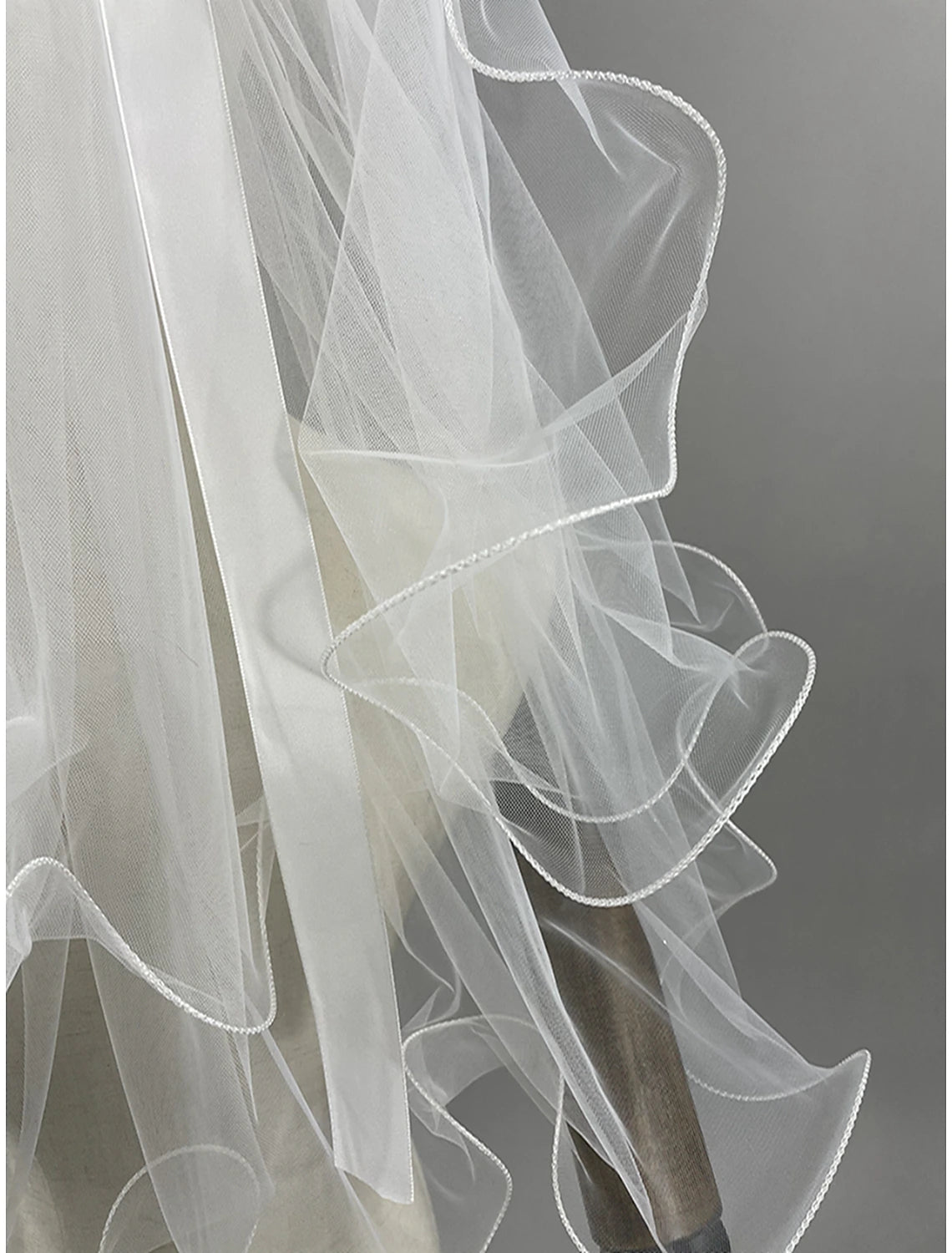 Close-up of the two-tier wedding veil showing the satin bow and delicate lace trim.