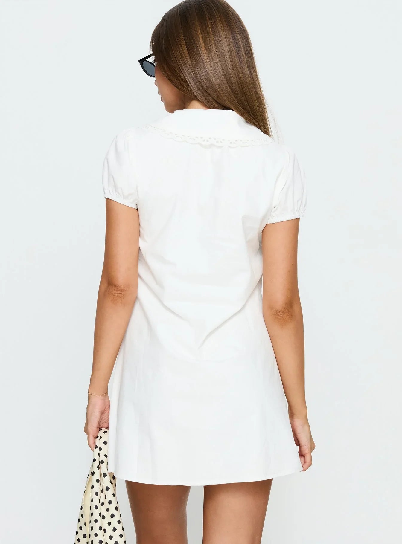 Side view of the white A-line mini dress, showing puff sleeves and keyhole tie neck.