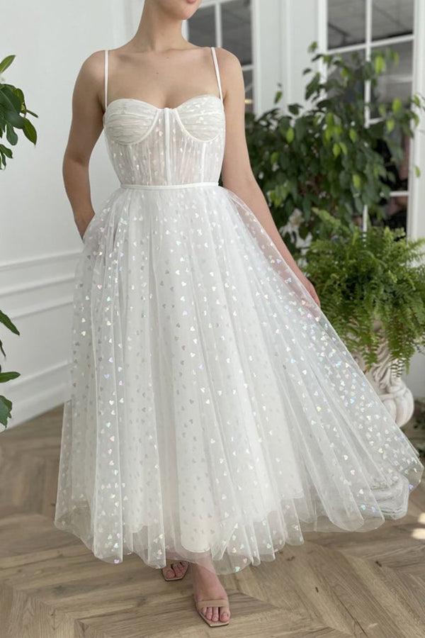 Woman wearing a sweetheart tulle A-line tea length homecoming dress with straps.