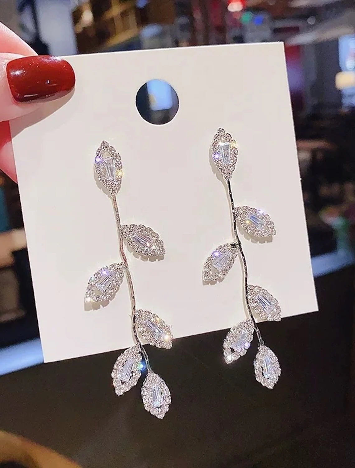 Model wearing S925 sterling silver geometrical leaf drop earrings, showcasing their length.