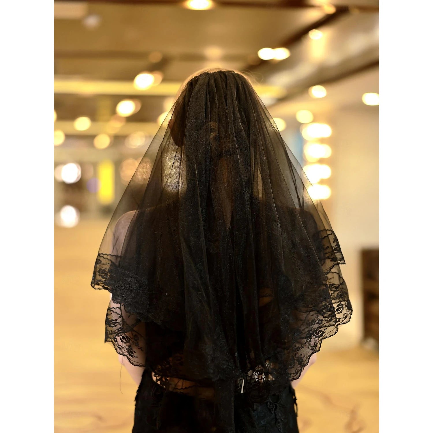 Bridal model wearing a two-tier elbow length wedding veil.