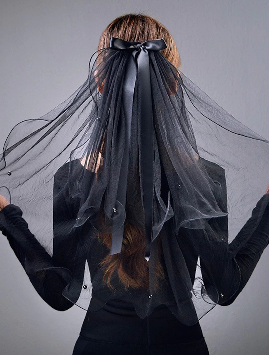 Close-up of the two-tier elbow veil, detailing faux pearls and a satin bow.