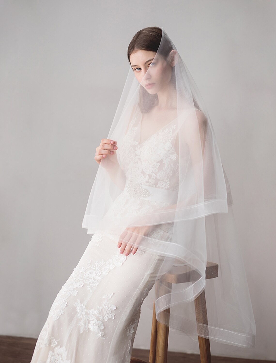 Back view of a bride wearing a two-tier fingertip veil, showcasing its length and drape.