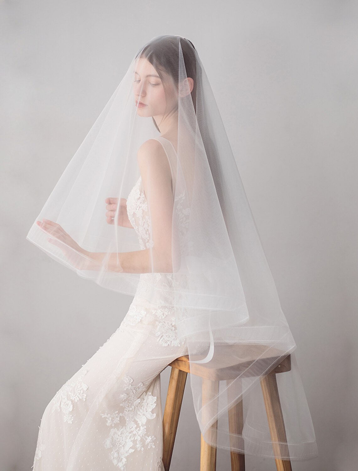 Side profile of a bride with a two-tier wedding veil, highlighting the sheer fabric.