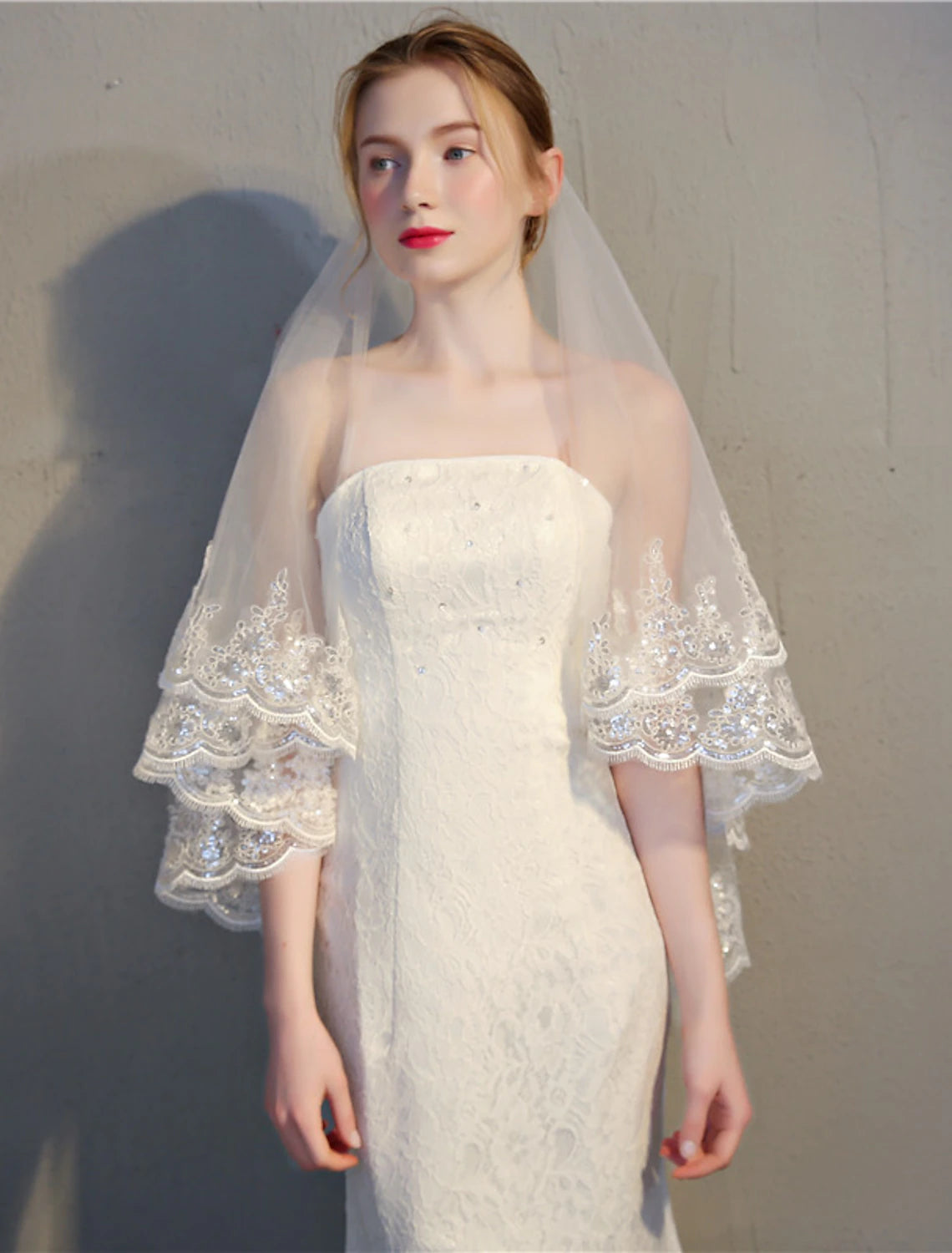 Two-tier fingertip wedding veil with delicate lace applique edge and subtle paillettes.