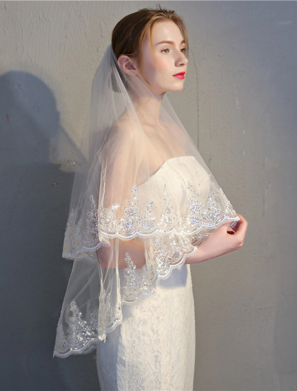 Close-up of the intricate lace applique and shimmering paillettes on the wedding veil.