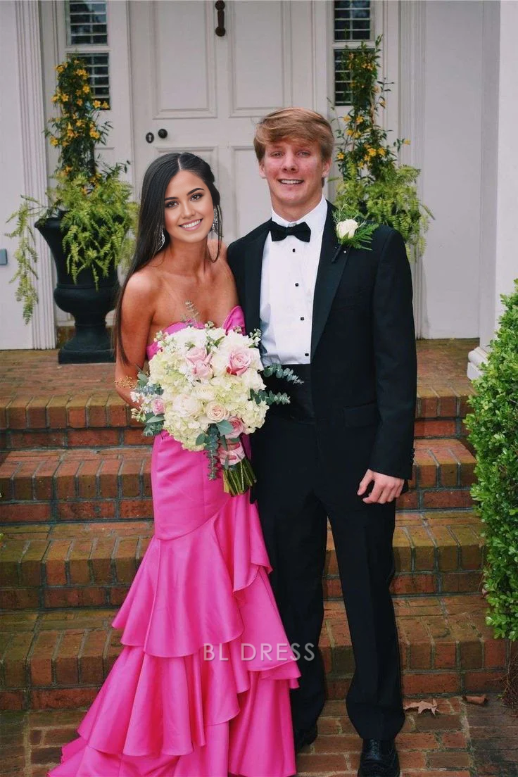 Woman wearing a vibrant hot pink mermaid formal dress with a sweetheart neckline and tiered satin fabric.