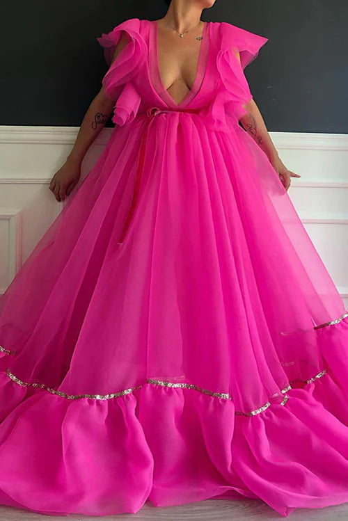 Side view of hot pink ball gown with voluminous skirt and ruffled sleeves.
