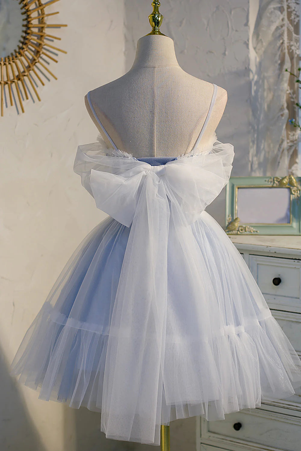 Back view of a model in a short blue tulle prom dress with lace appliques.