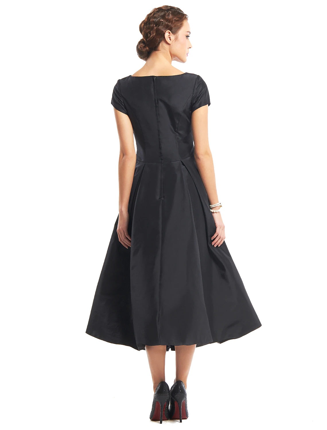 Side view of a woman in a black tea length A-line dress with buttons.