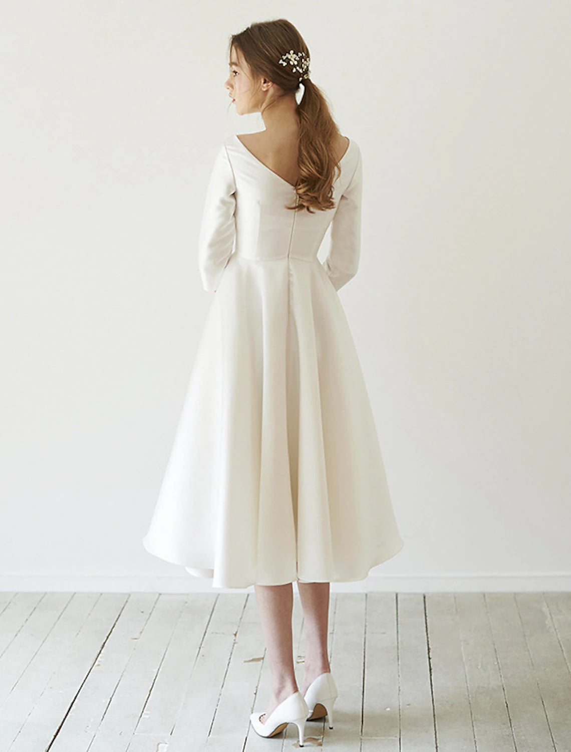 Back view of a vintage A-line satin wedding dress with a scoop neck and 3/4 sleeves.