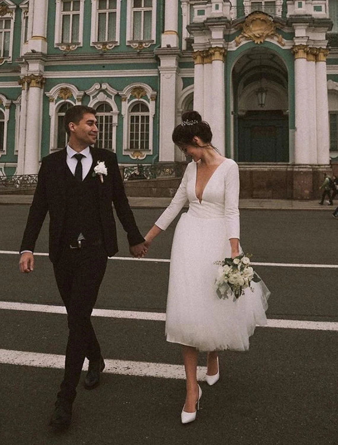 Elegant white satin bridal gown with long sleeves and V-neckline.