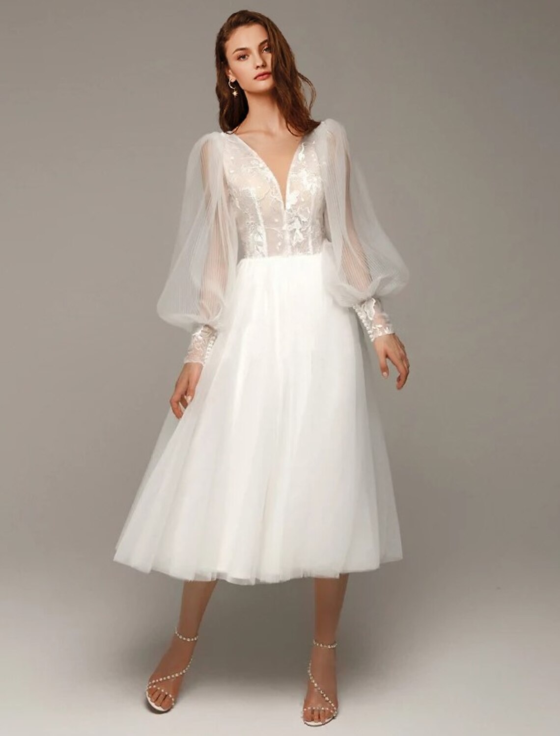 Front view of a white vintage A-line wedding dress with V-neck and long sleeves.