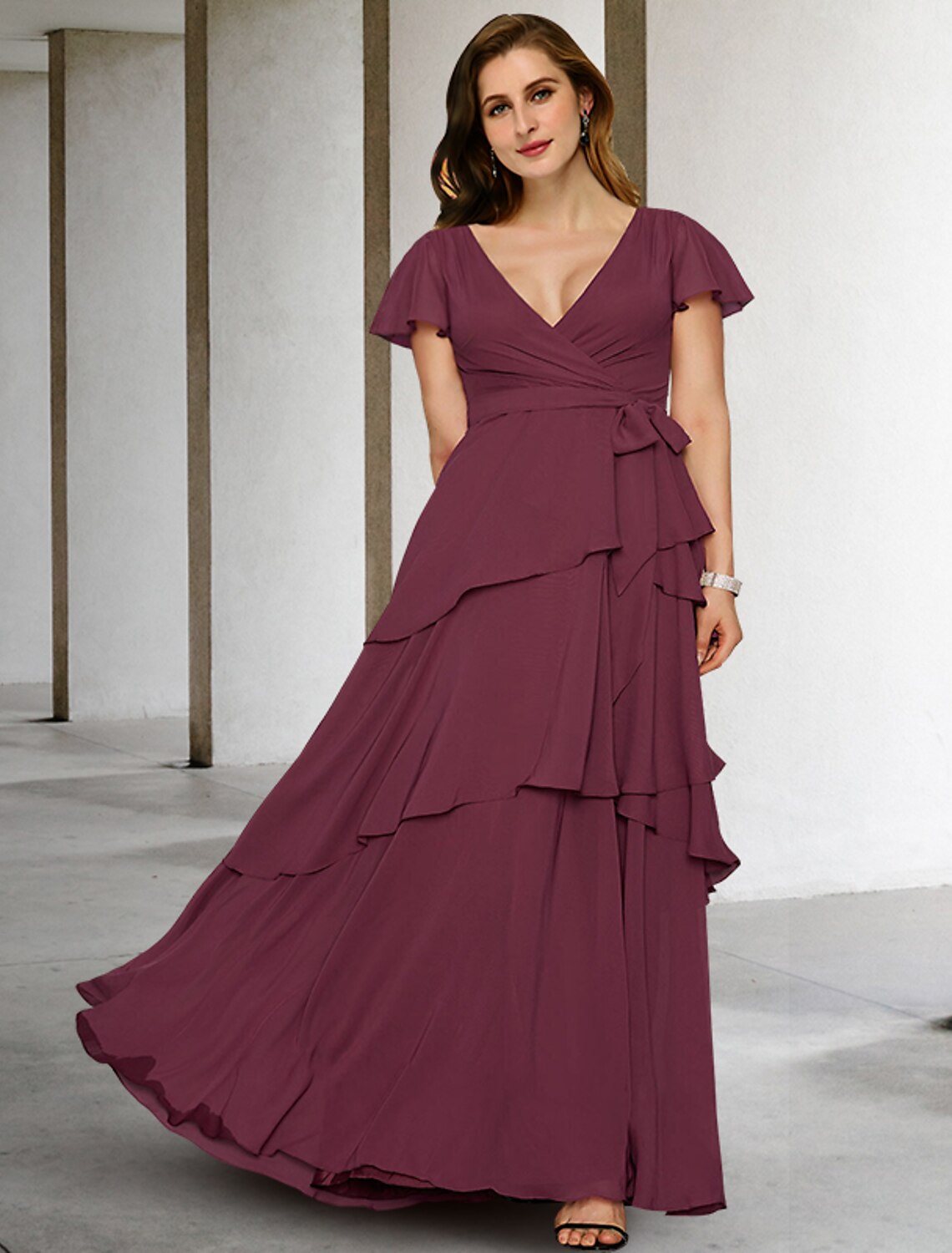 Front view of a woman wearing an elegant A-line plus size mother of the bride dress.