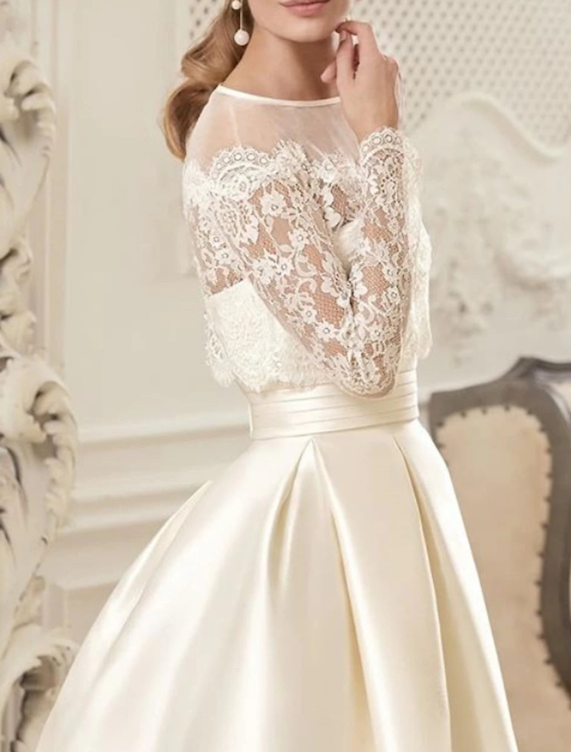 Side view of an elegant ivory satin bridal gown featuring an illusion neckline, long sleeves, and delicate beading.