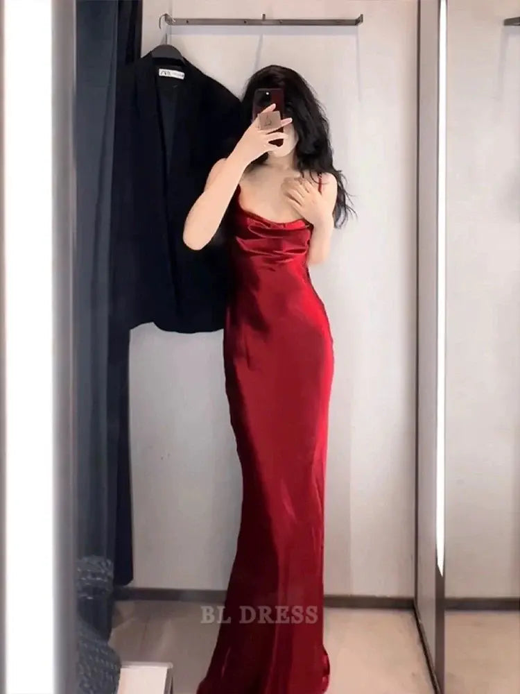 Woman wearing a vintage burgundy mermaid gown with spaghetti straps.