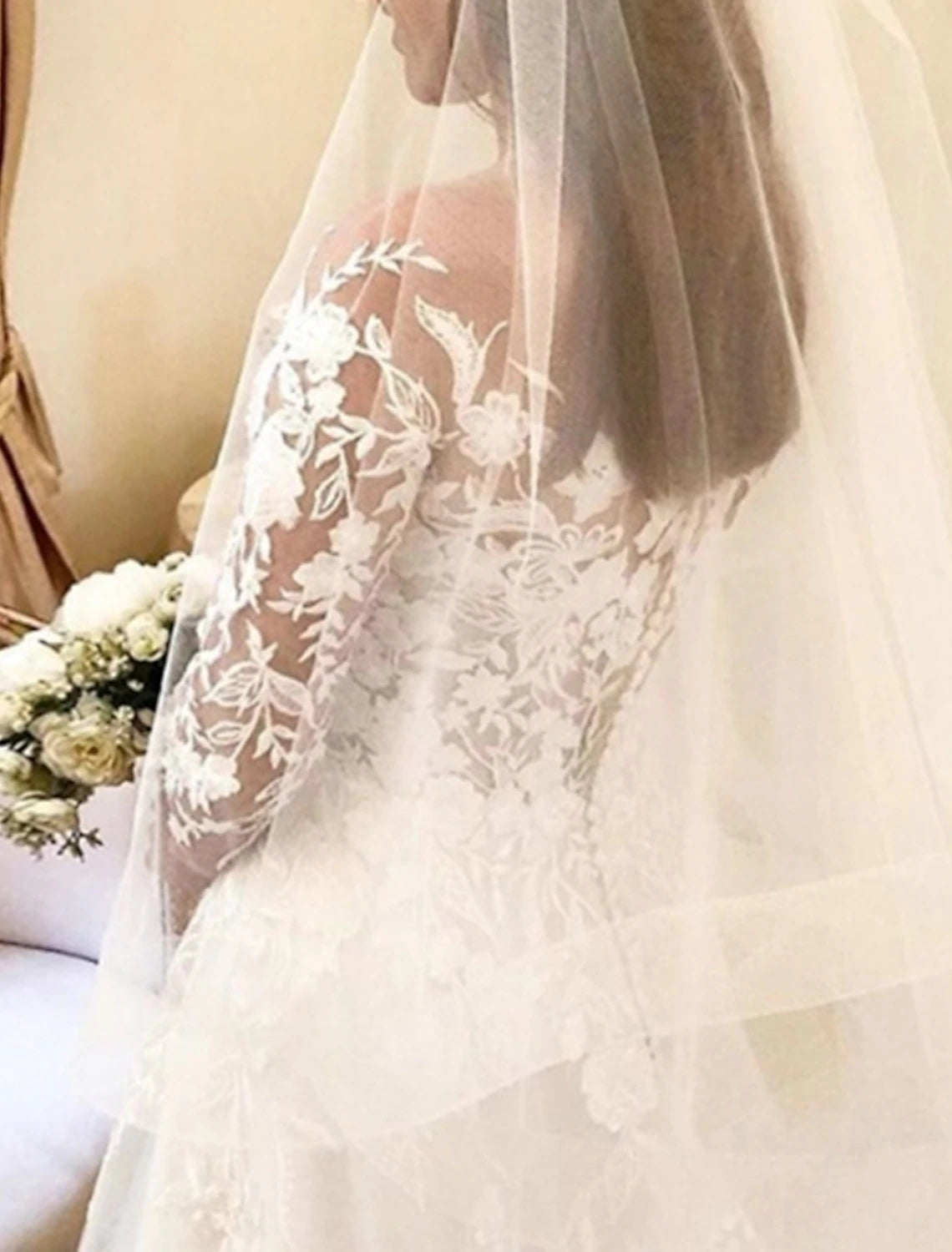 Side view of elegant off-shoulder bridal gown with long sleeves and lace details.