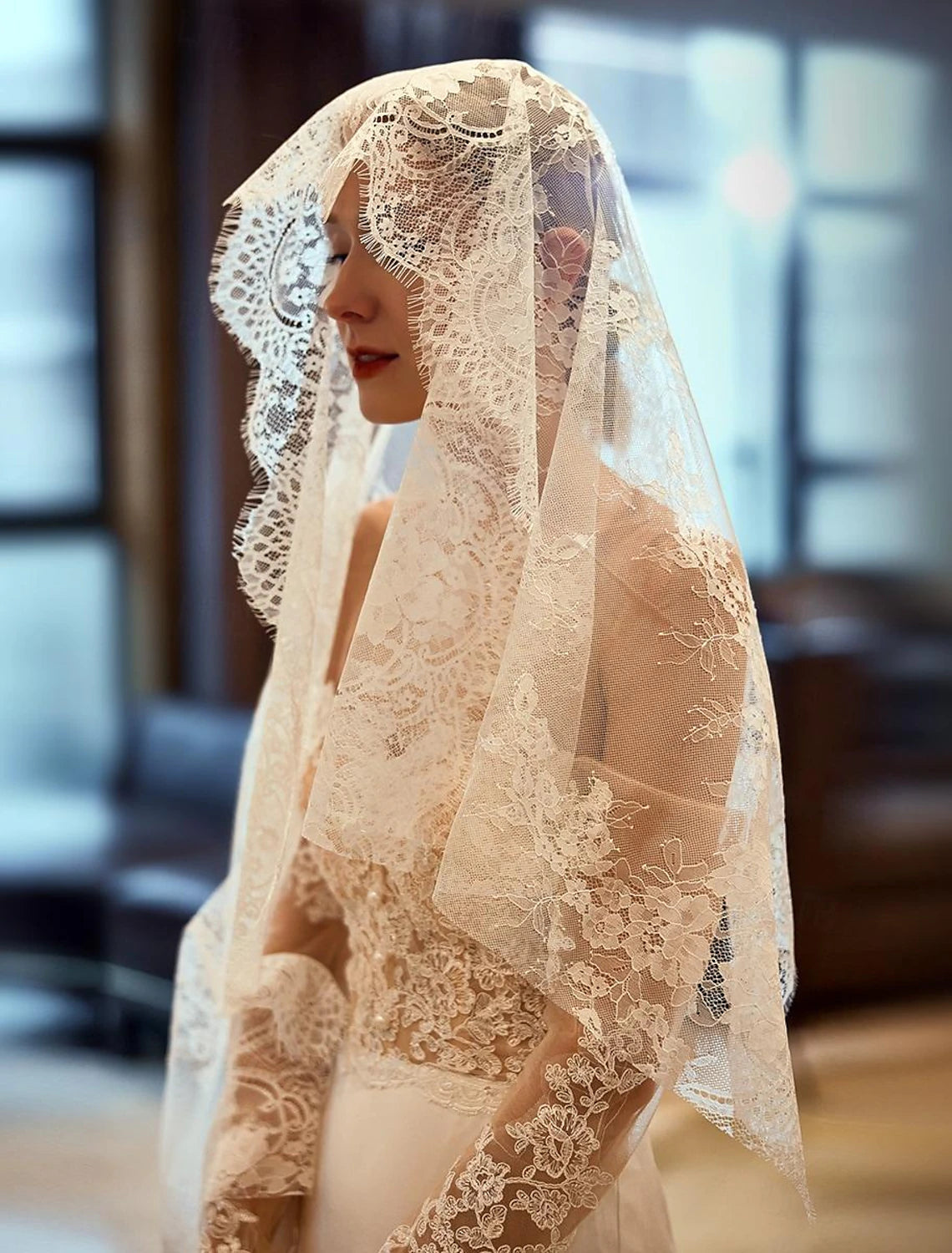 Close-up of the intricate lace embroidery on the elbow-length wedding veil.