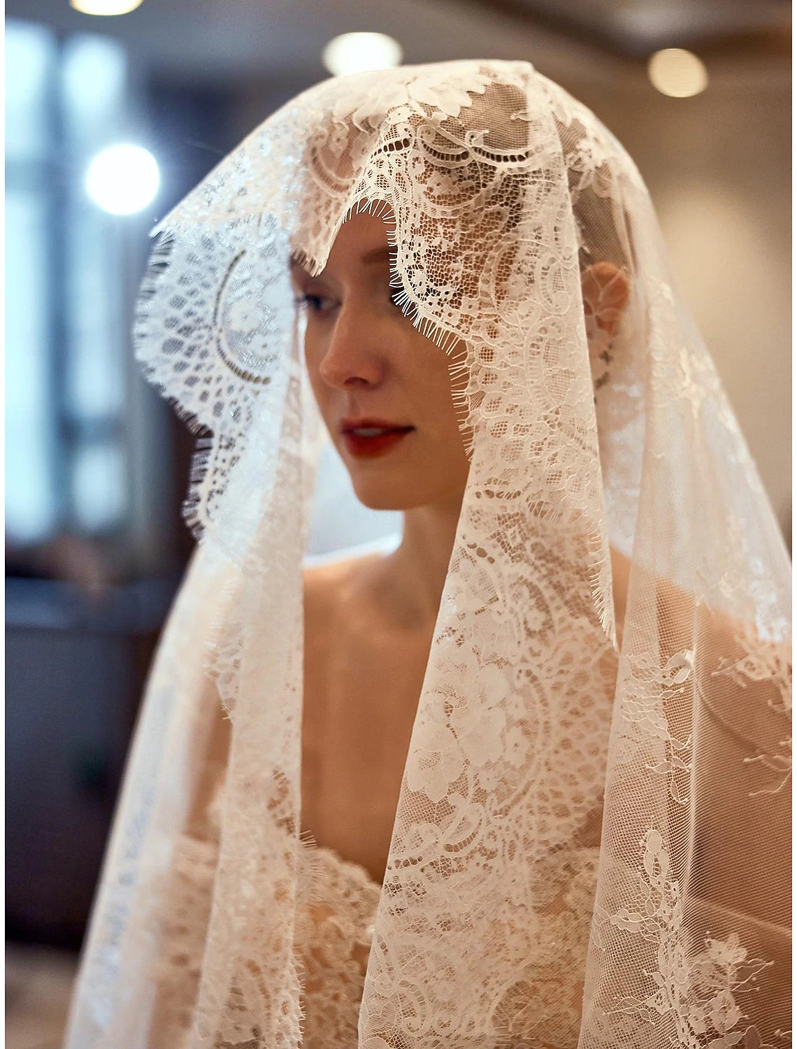 Bride posing gracefully with the elbow-length wedding veil, highlighting its flow.