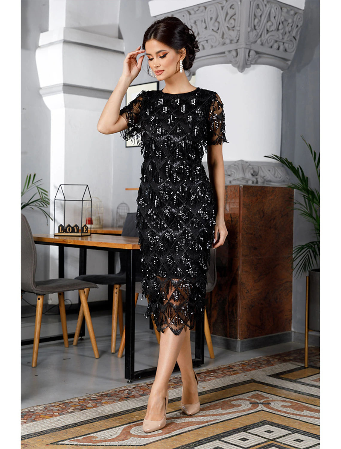 Woman wearing a vintage sheath tea length party dress with short sleeves and jewel neck, featuring tassel and embroidery.