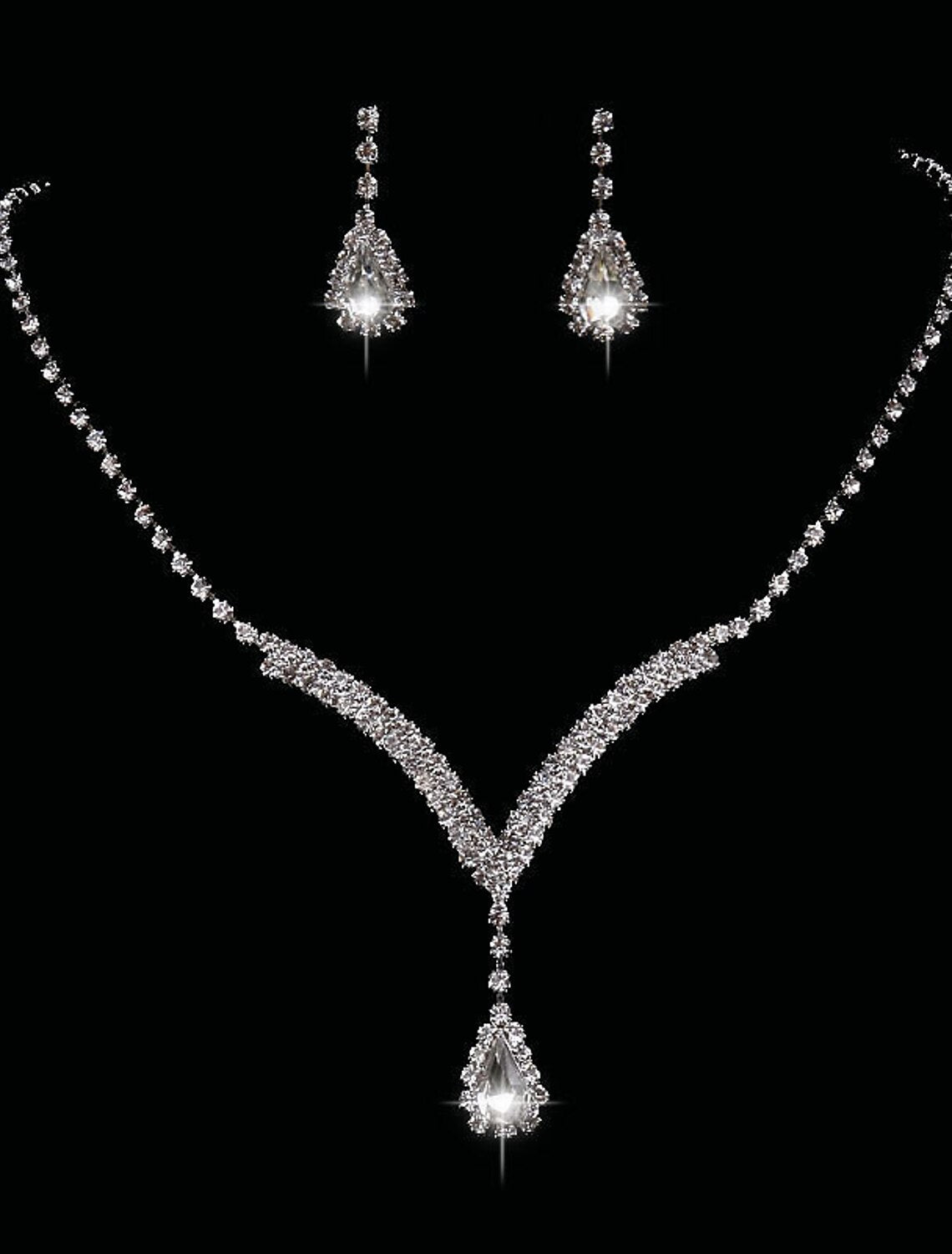 Woman wearing a vintage teardrop synthetic diamond jewelry set with drop earrings and a matching necklace.