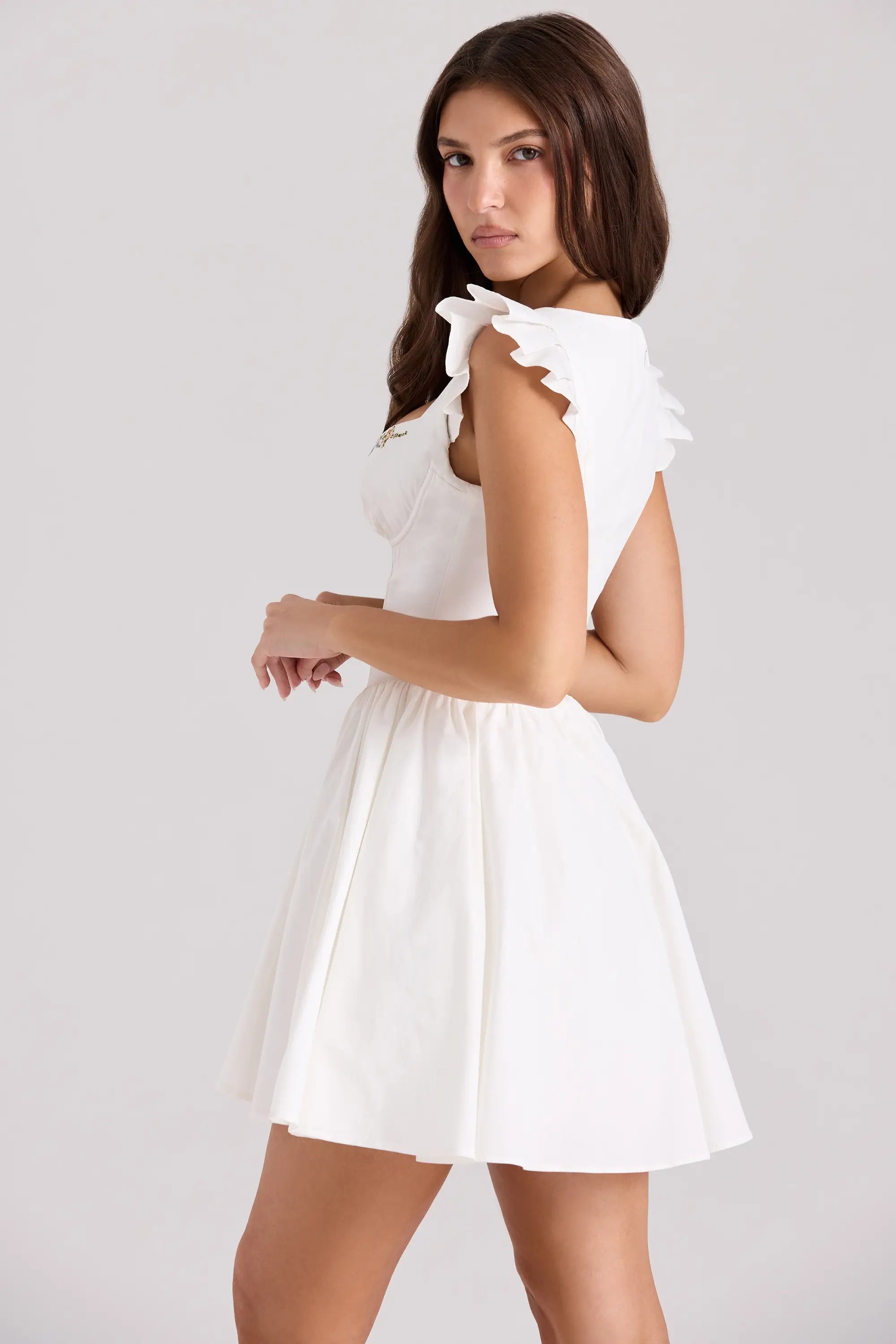 Back view of white floral embroidered mini dress with ruffle straps.