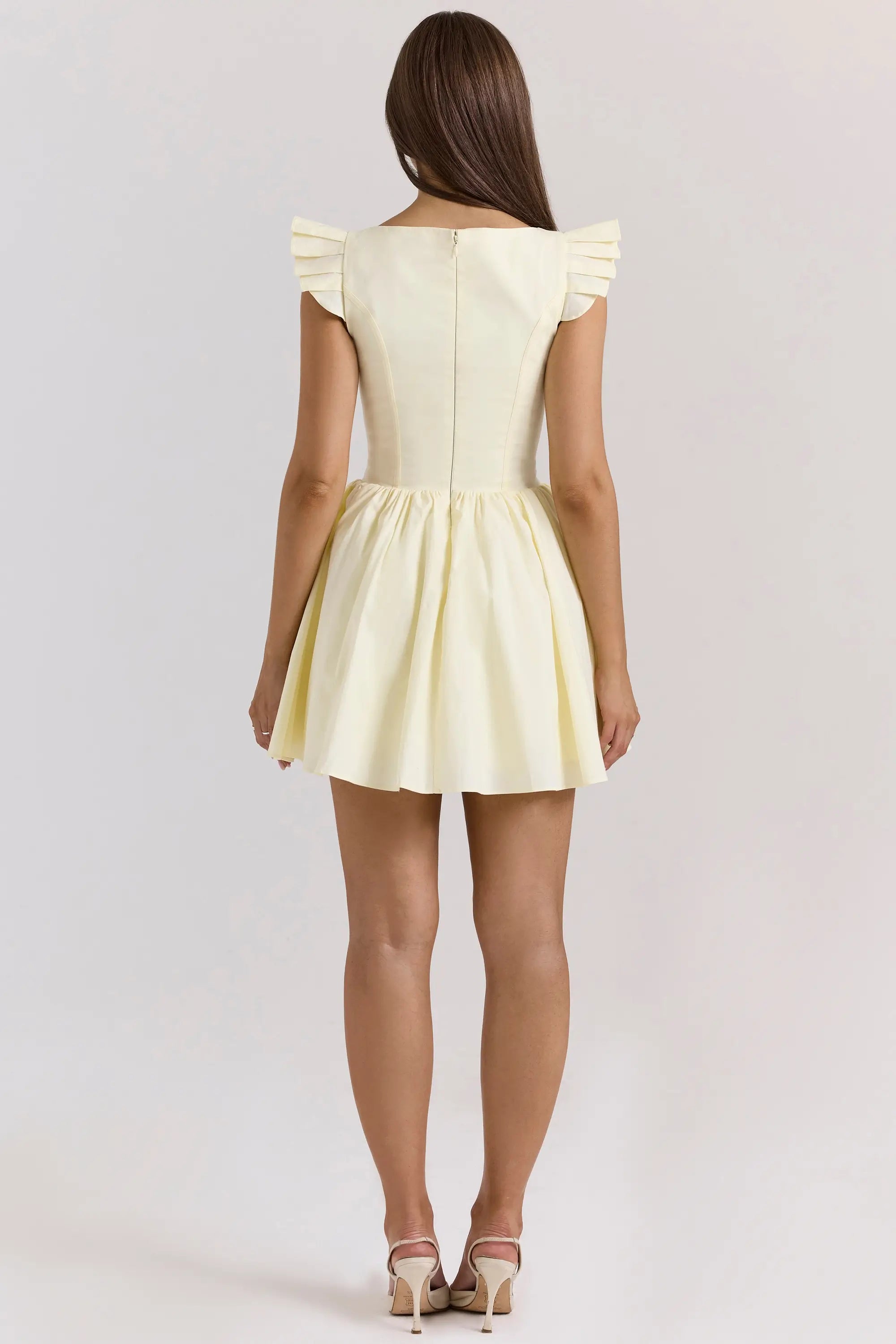 Model posing in a white floral embroidered mini homecoming dress.