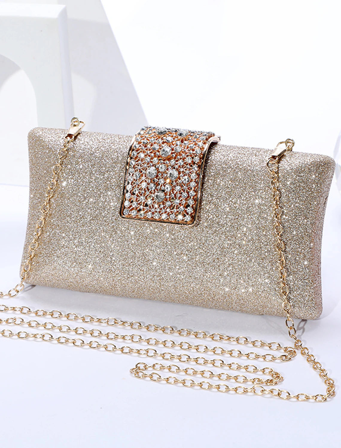 Woman holding a solid color crystal clutch bag with a chain.