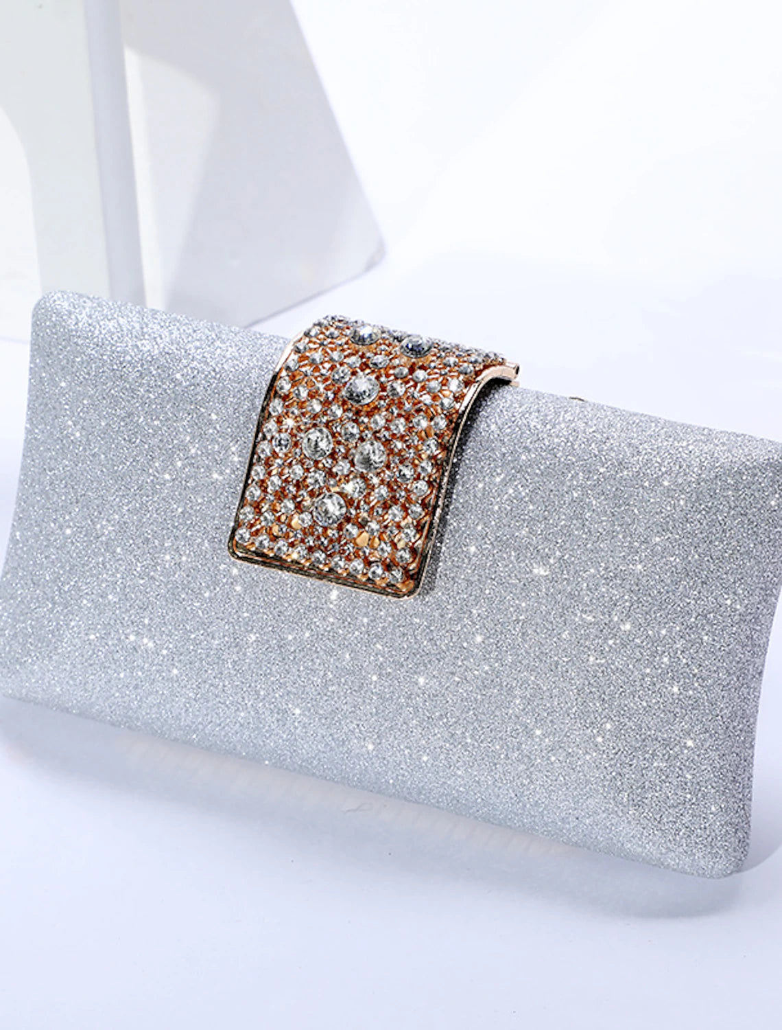 Hand holding a solid color crystal clutch bag for an evening event.