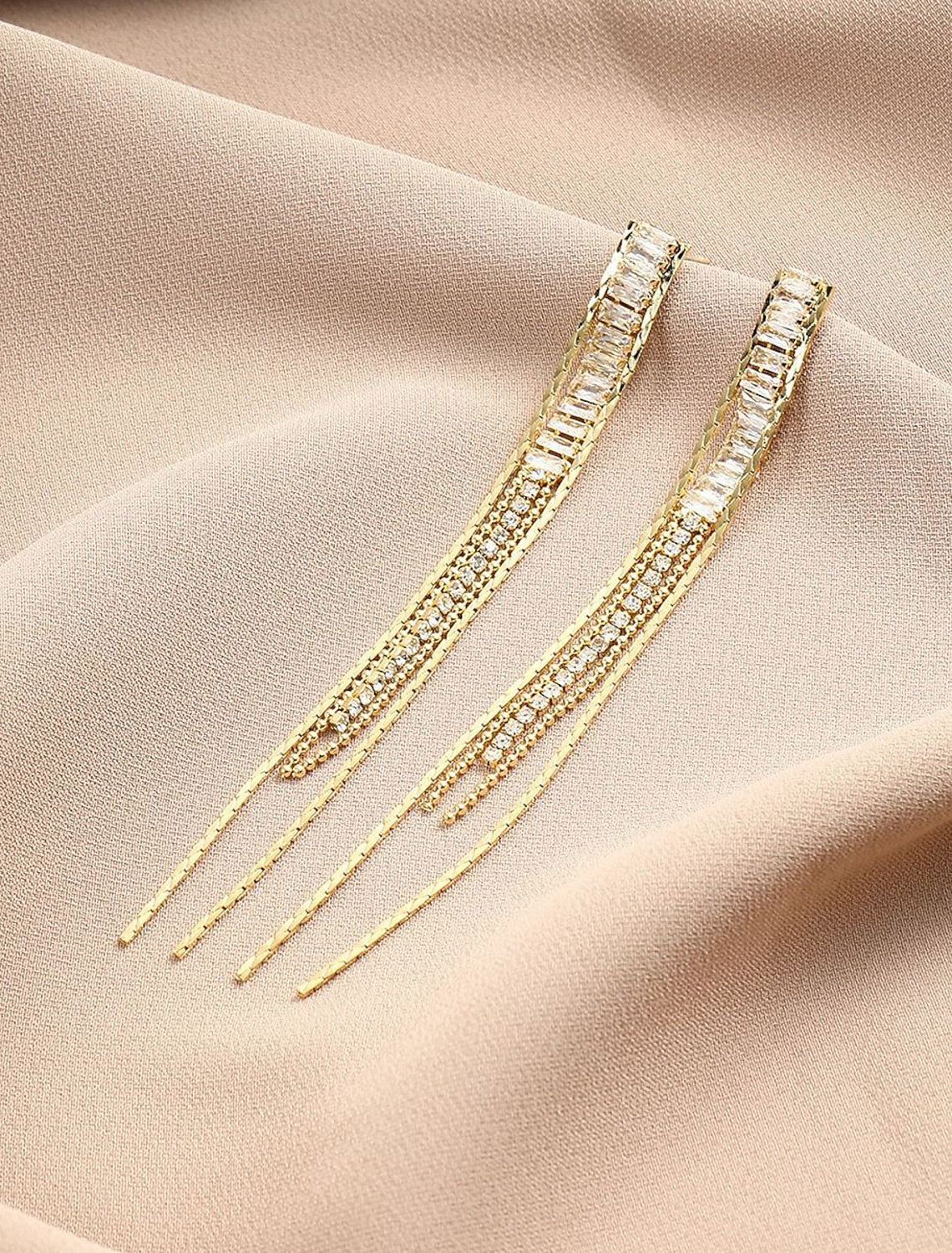 Close-up of a single brown drop earring with gold-tone tassel.
