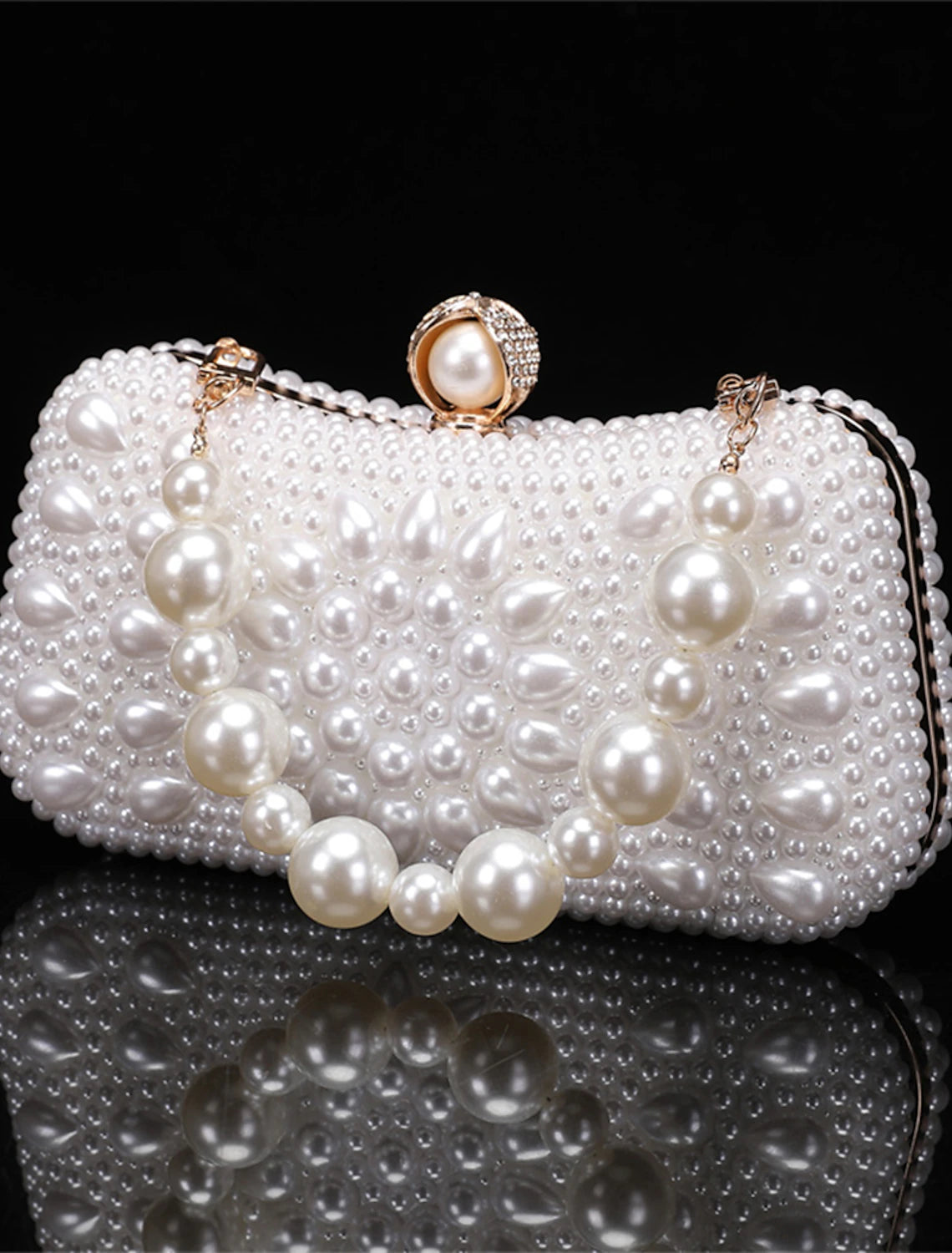 Woman holding a geometric leather clutch bag with pearl chain.