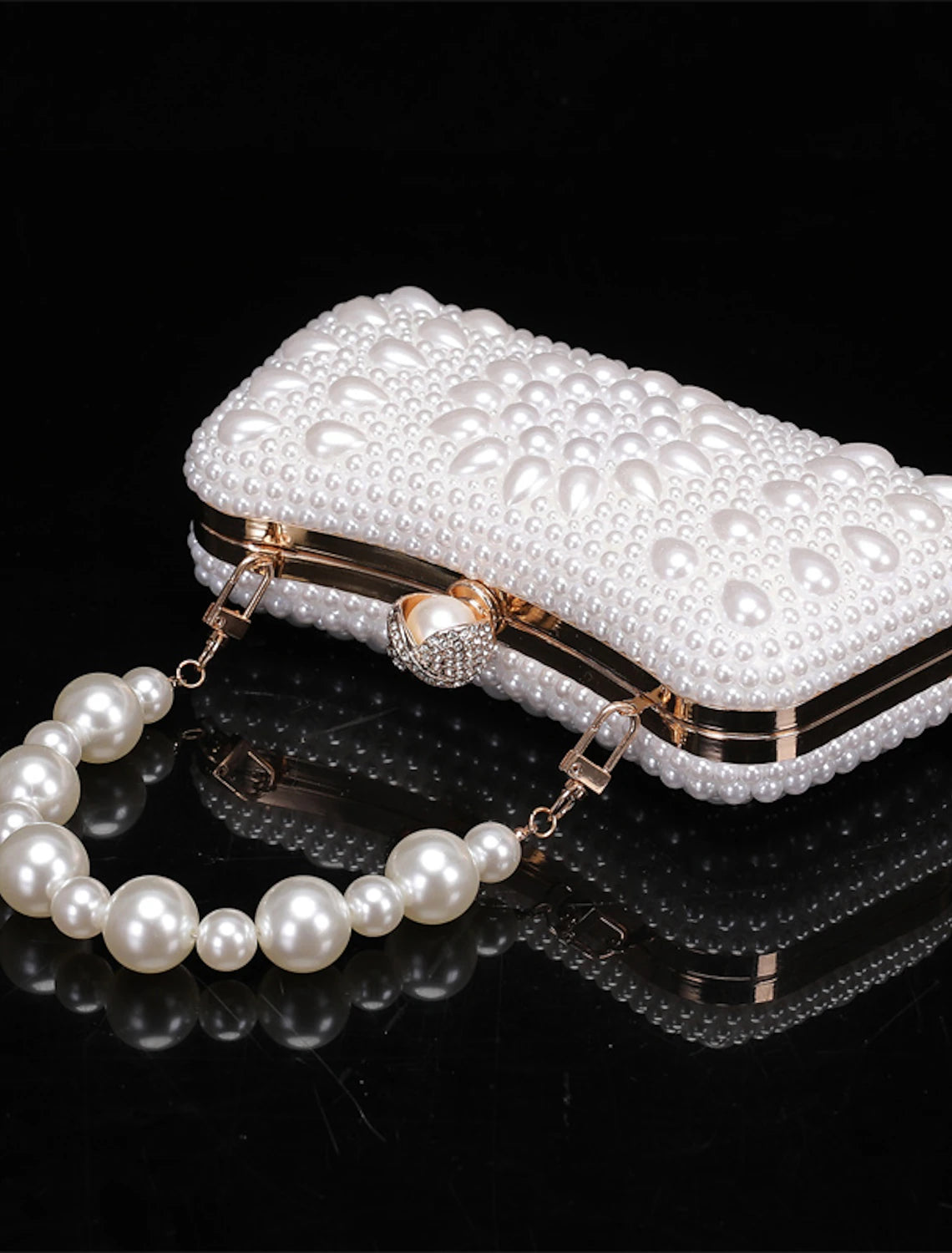 Elegant geometric clutch bag with pearl chain, held by a hand.