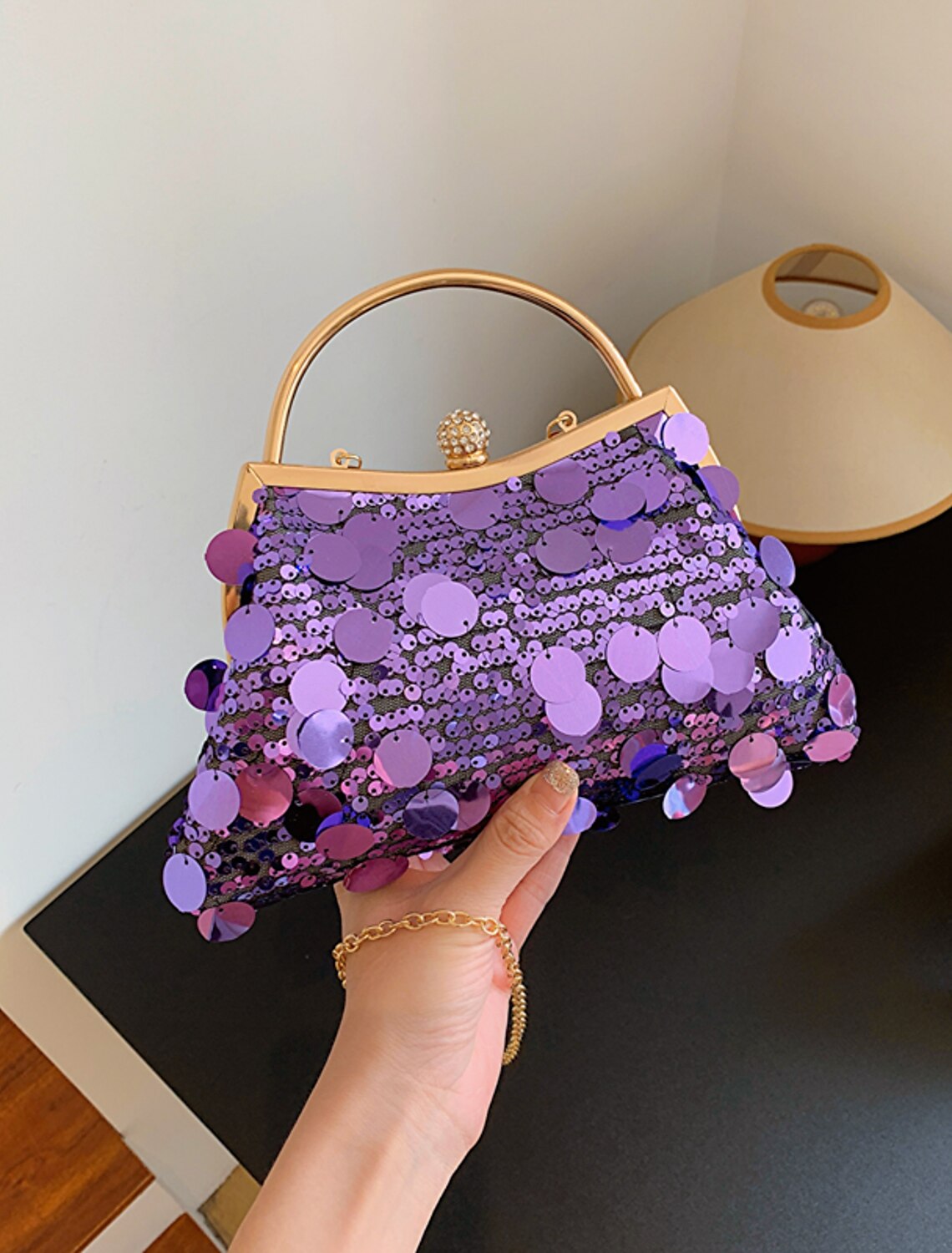 Side view of foldable dome evening bag with tassel.