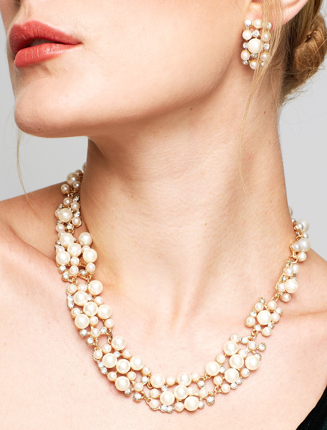 Close-up of twisted gold-tone drop earrings with pearls and rhinestones.