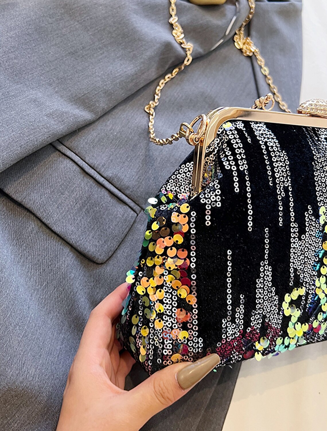 Woman holding a sequin geometric dome clutch bag.