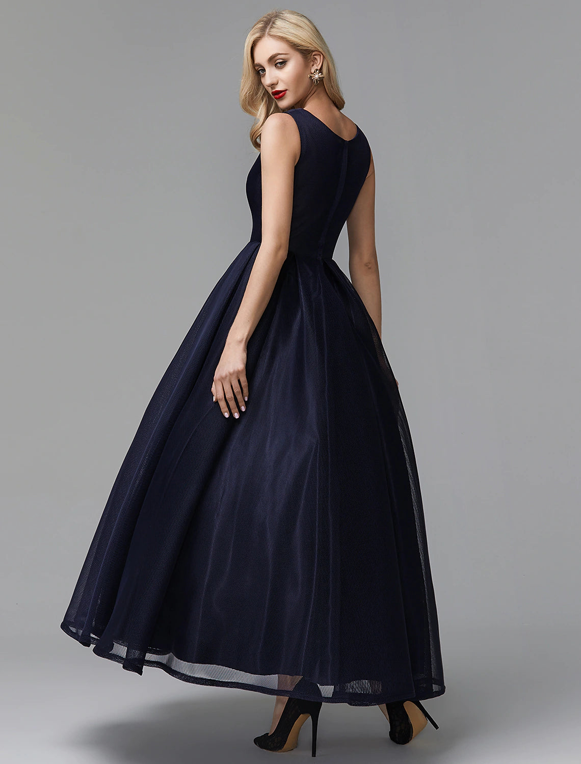 Side profile of the sleeveless black wedding guest dress.