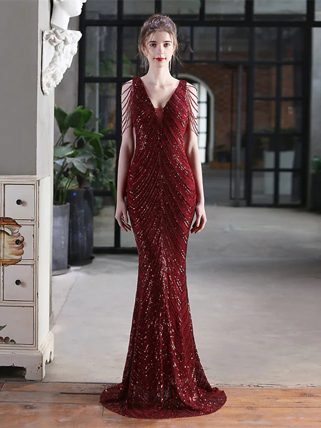 A woman walking in a sequined V-neck mermaid trumpet evening gown, showcasing the floor-length silhouette.