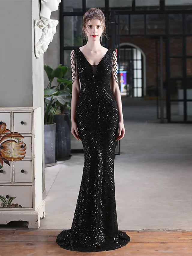 A woman standing in a sequined V-neck mermaid trumpet evening gown, highlighting the overall design.
