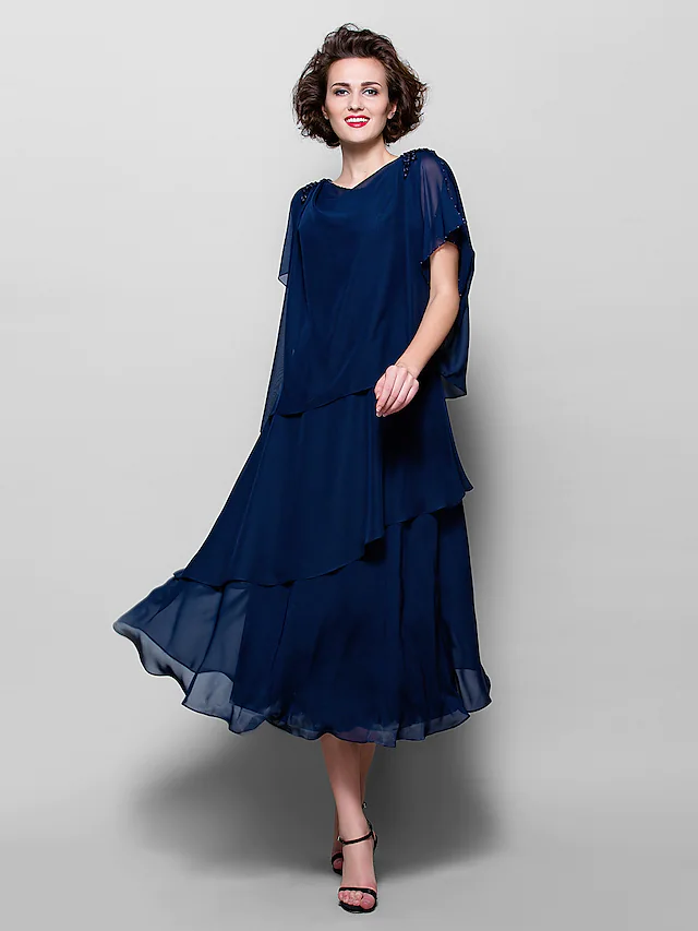 Woman wearing an elegant A-line cowl neck short sleeve tea length chiffon dress with ruffles.