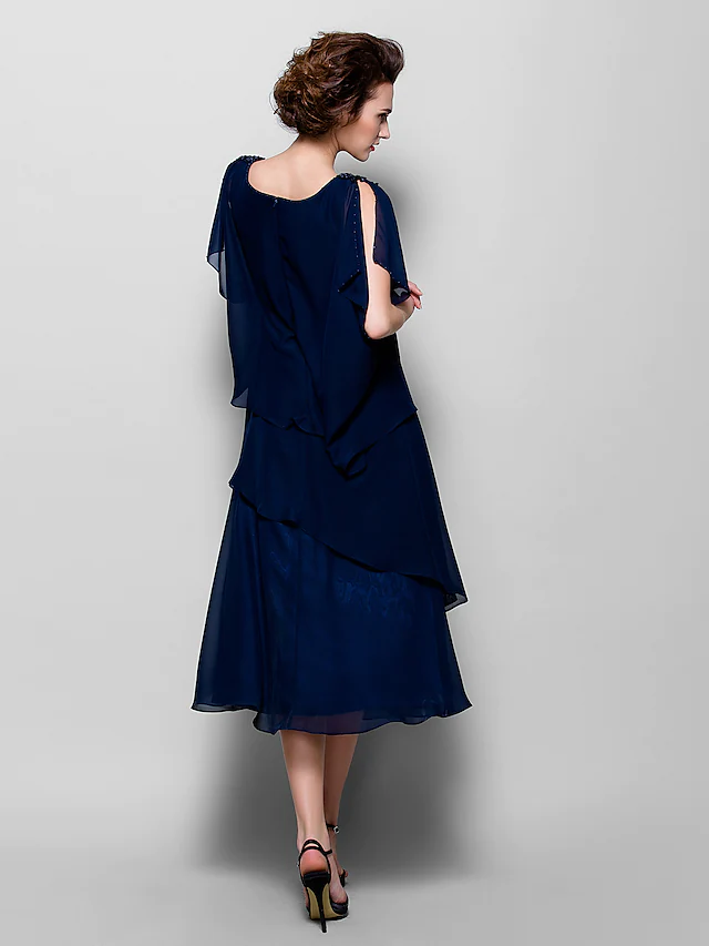 Side view of a woman in an A-line cowl neck short sleeve tea length chiffon dress, showing ruffles.
