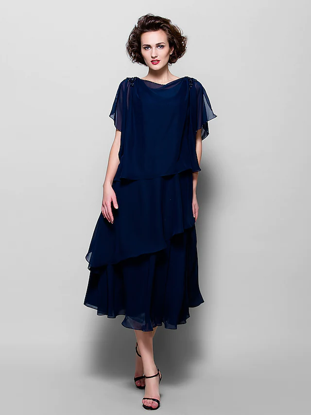 Back view of a woman in an A-line cowl neck short sleeve tea length chiffon dress, highlighting the silhouette.