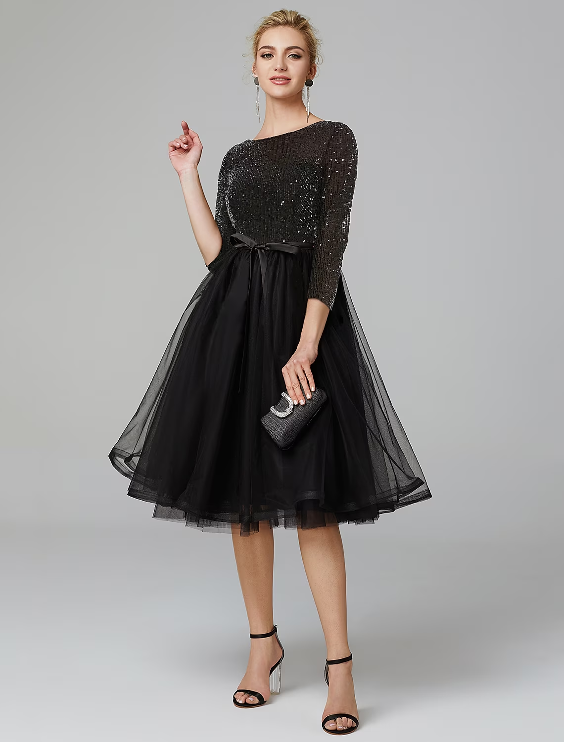 Model wearing a sparkling navy A-line tea length cocktail dress with 3/4 sleeves and a jewel neck, front view.