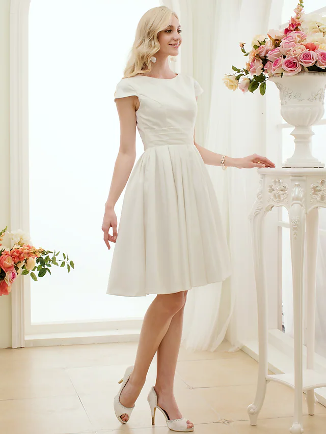 Side view of the knee-length satin wedding dress.
