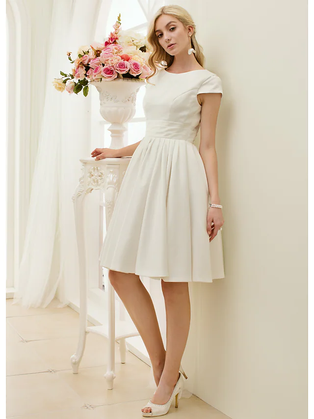 Close-up of the jewel neck and short sleeve detail on the white dress.